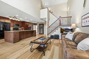 Living area featuring light wood-style floors, a high ceiling, and recessed lighting