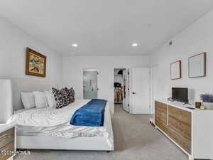 Bedroom featuring light carpet, a spacious closet, recessed lighting, and ensuite bathroom