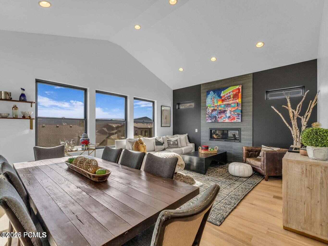 Dining area with recessed lighting, a fireplace, vaulted ceiling, light wood-style floors, and an accent wall