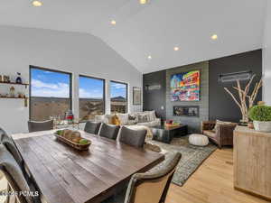 Dining area with recessed lighting, a fireplace, vaulted ceiling, light wood-style floors, and an accent wall