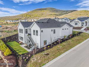 View of side of home with a yard, roof with shingles, a mountain view, and board and batten siding