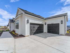 View of home's exterior featuring roof with shingles, board and batten siding, concrete driveway, and a garage