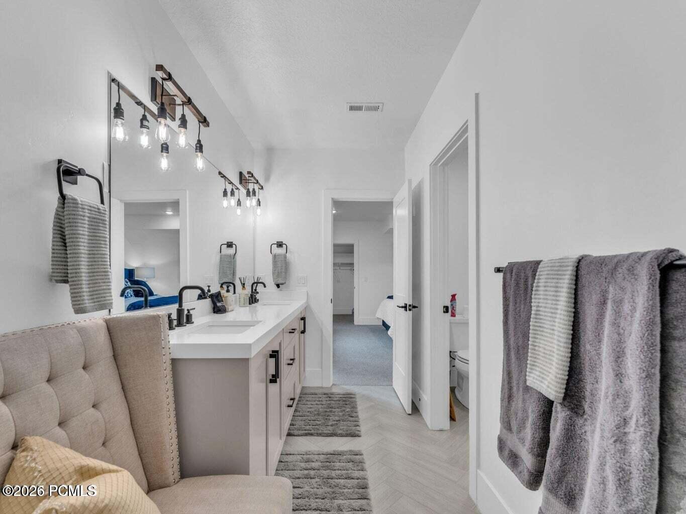 Bathroom with double vanity, connected bathroom, and parquet flooring