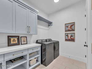 Laundry room with independent washer and dryer, cabinet space, and light tile patterned floors