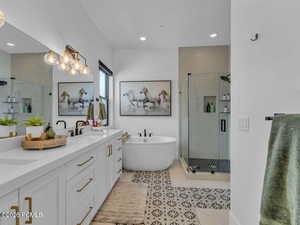 Full bathroom featuring double vanity, a stall shower, a soaking tub, light tile patterned floors, and recessed lighting