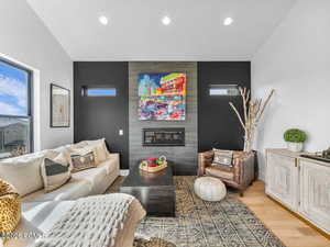 Living area with a tiled fireplace, light wood-style floors, recessed lighting, plenty of natural light, and an accent wall