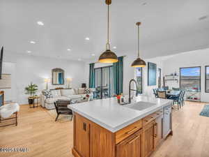 Kitchen with open floor plan, wood finish cabinetry, light wood finished floors, and a kitchen island with sink