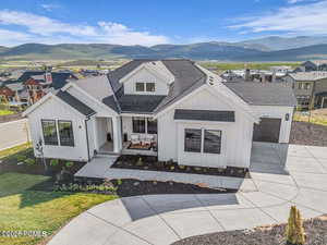 Modern inspired farmhouse featuring a shingled roof, concrete driveway, board and batten siding, and an attached garage