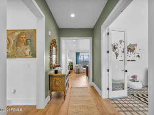 Hall with light wood finished floors and recessed lighting