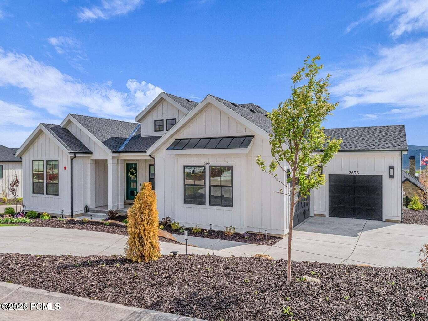Modern farmhouse style home featuring board and batten siding, a shingled roof, a standing seam roof, and a garage
