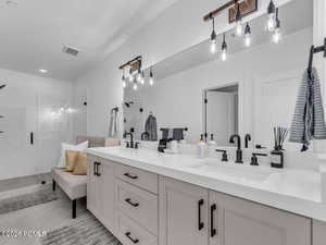 Full bathroom with double vanity and a shower stall