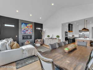 Dining area with recessed lighting, light wood-style flooring, a large fireplace, and vaulted ceiling