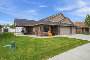 Ranch-style house with brick siding, a garage, a shingled roof, driveway, and a shed