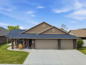 View of front of house with roof with shingles, an attached garage, a front lawn, driveway, and covered porch