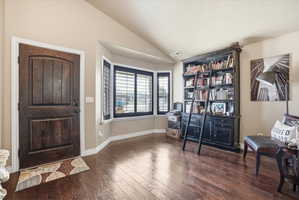 Foyer entrance featuring vaulted ceiling and dark wood-style flooring