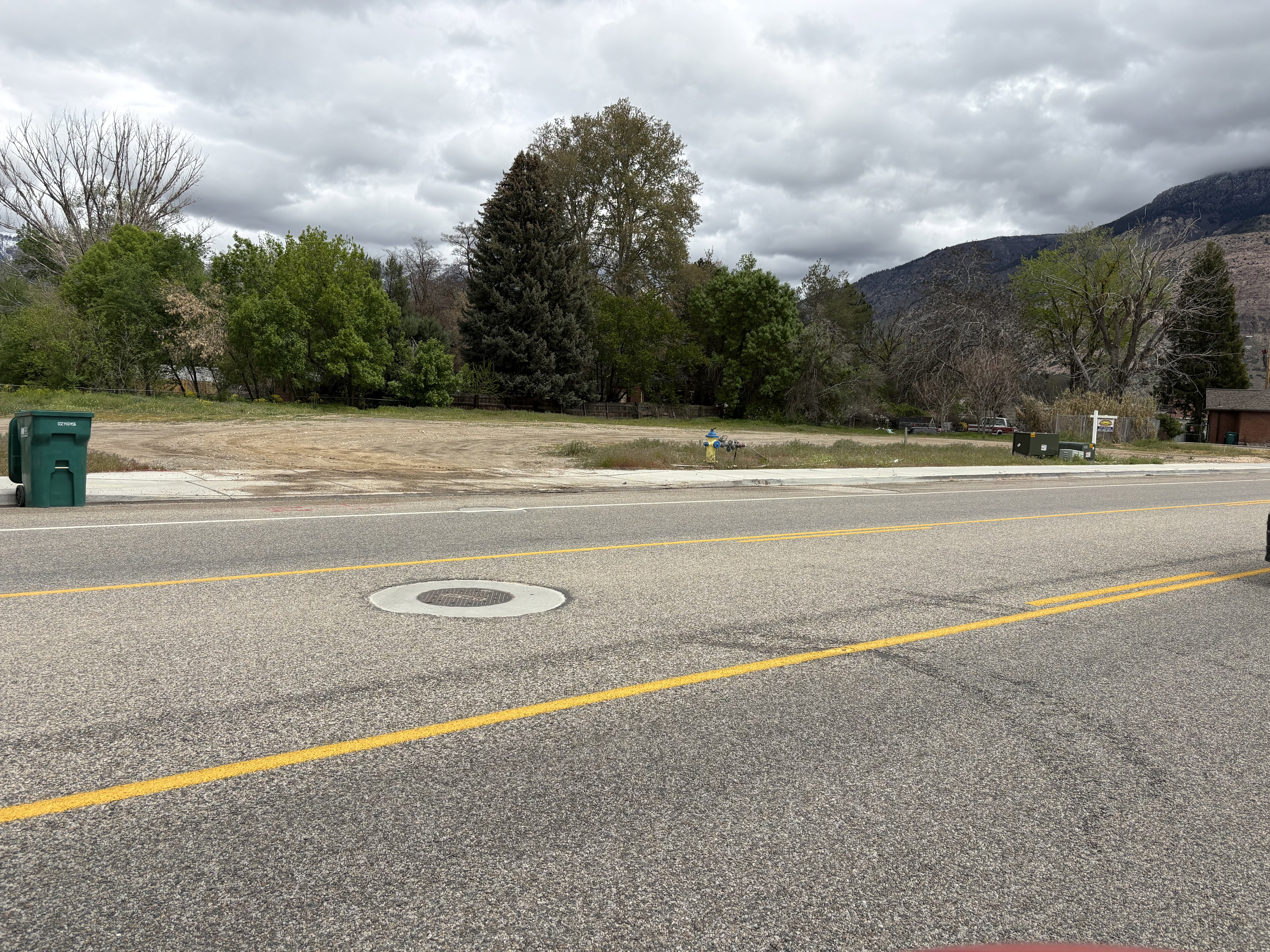 View of asphalt road with sidewalks and a mountain view