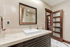 Bathroom featuring vanity, a shower, and light marble finish floors