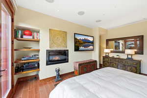 Bedroom featuring wood tiled floors and a glass covered fireplace