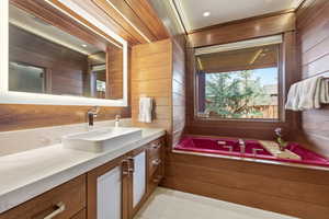 Full bath with vanity, wooden walls, and a bath