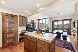 Kitchen featuring wood finish cabinets, light countertops, light wood finished floors, a center island, and pendant lighting