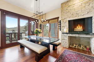Dining space with a warm lit fireplace and wood finished floors