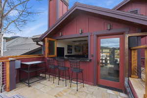 Property entrance featuring a standing seam roof, a chimney, and a patio