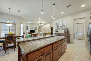 Kitchen with a center island, dark stone counters, hanging light fixtures, light tile patterned floors, and freestanding refrigerator