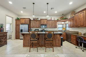 Kitchen with a breakfast bar, stainless steel appliances, a center island, and dark stone countertops