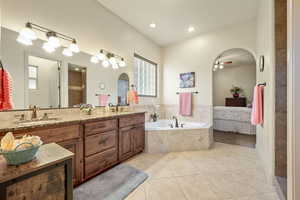 Full bath with double vanity, light tile patterned floors, ensuite bathroom, a bath, and a tile shower