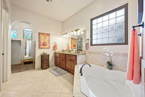Full bathroom with double vanity, a tub with jets, and light tile patterned floors