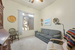 Carpeted living area featuring ceiling fan and vaulted ceiling