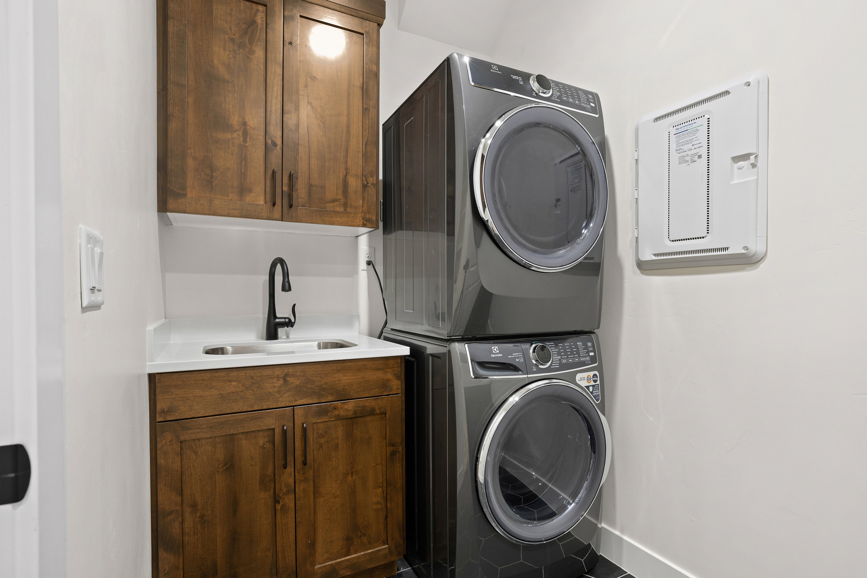 Laundry room with stacked washer and clothes dryer and cabinet space