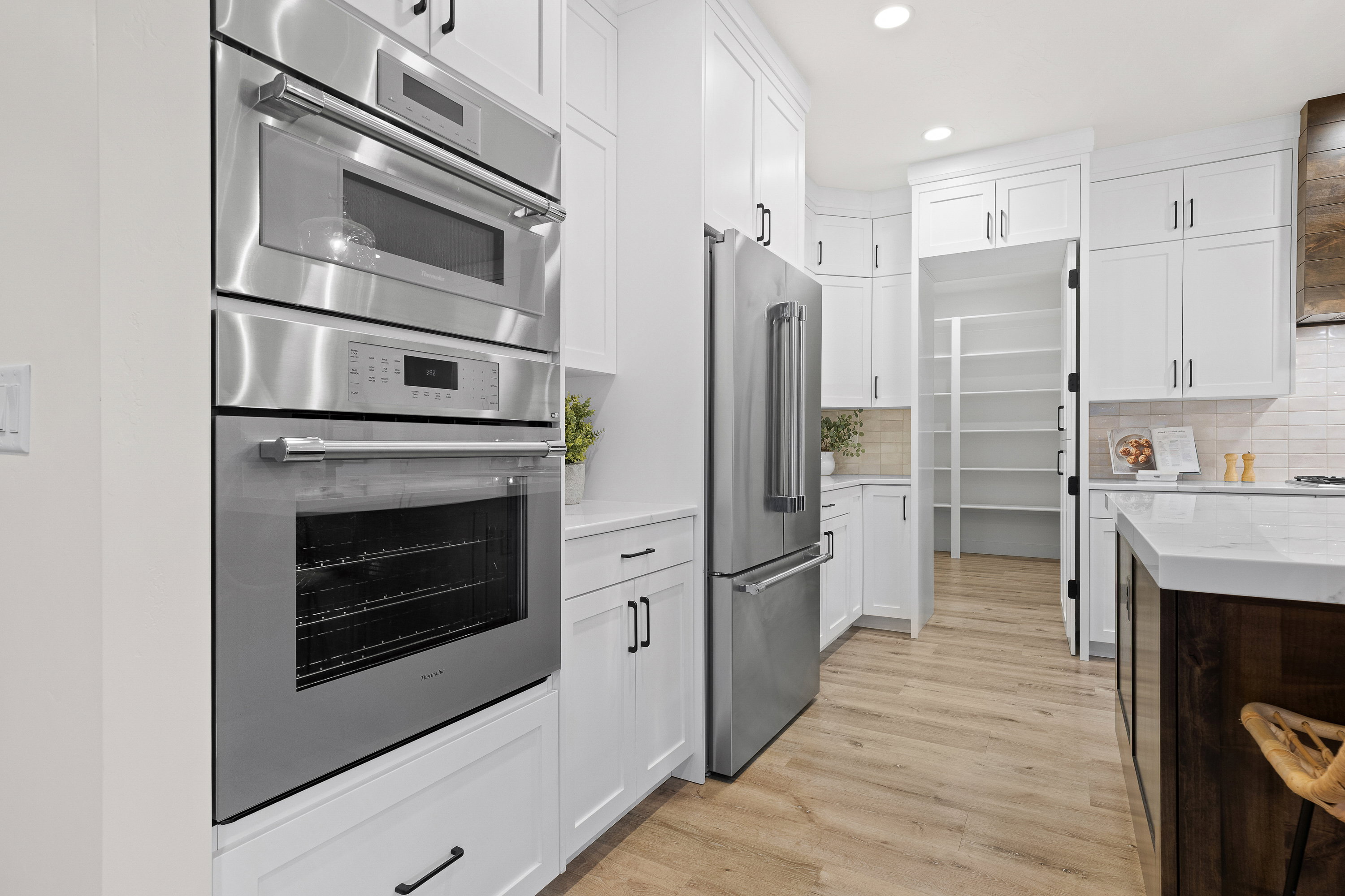 Kitchen with stainless steel appliances, recessed lighting, light stone countertops, two tone cabinets, and light wood-style flooring