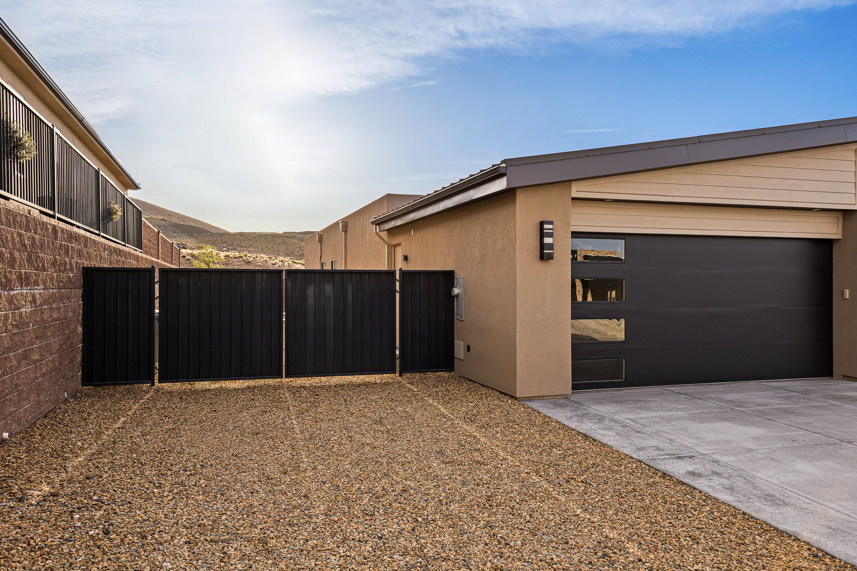 View of side of home featuring a gate, a garage, stucco siding, and driveway