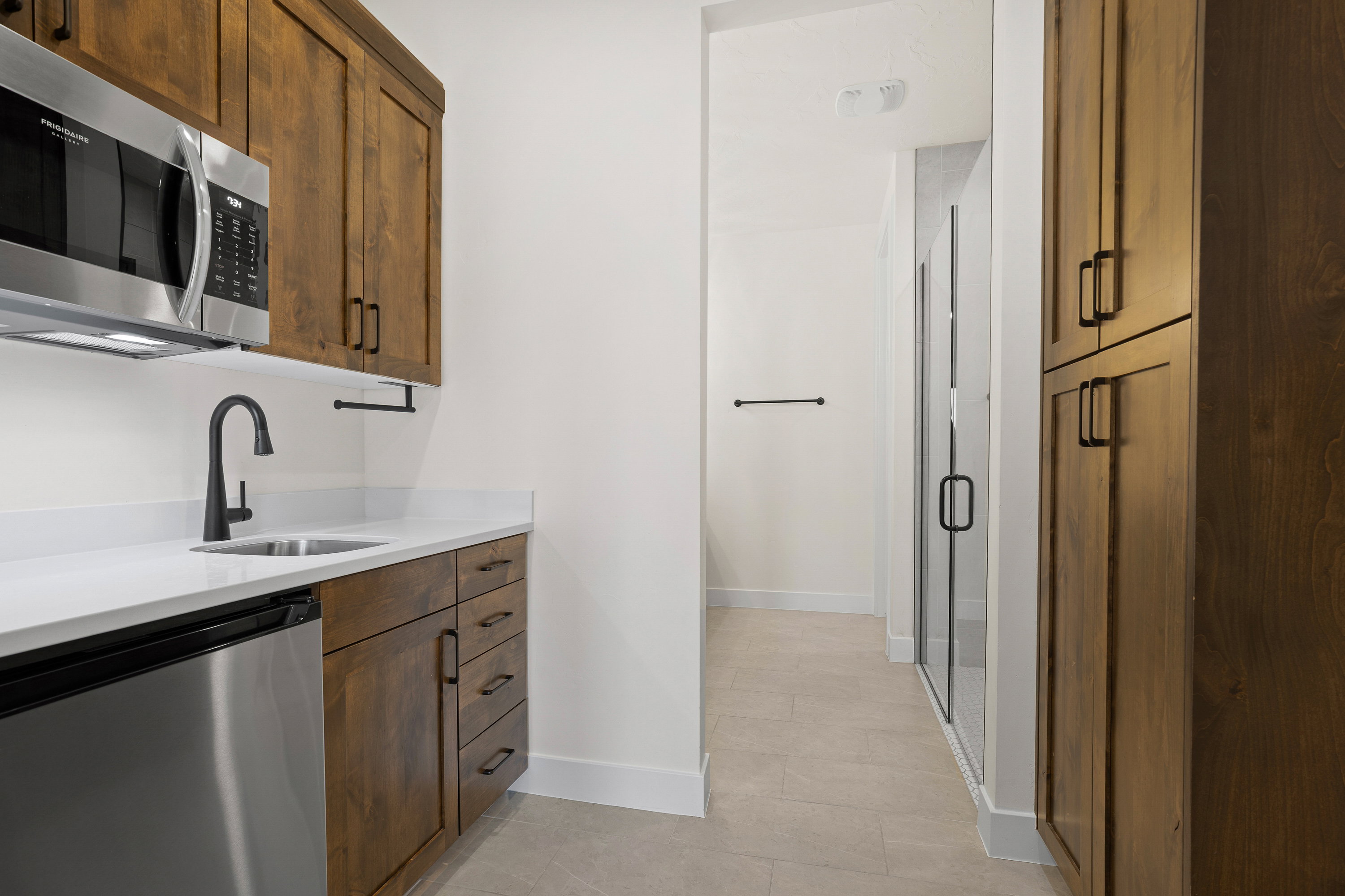 Kitchen with stainless steel appliances, light stone countertops, light tile patterned flooring, and wood finish cabinetry