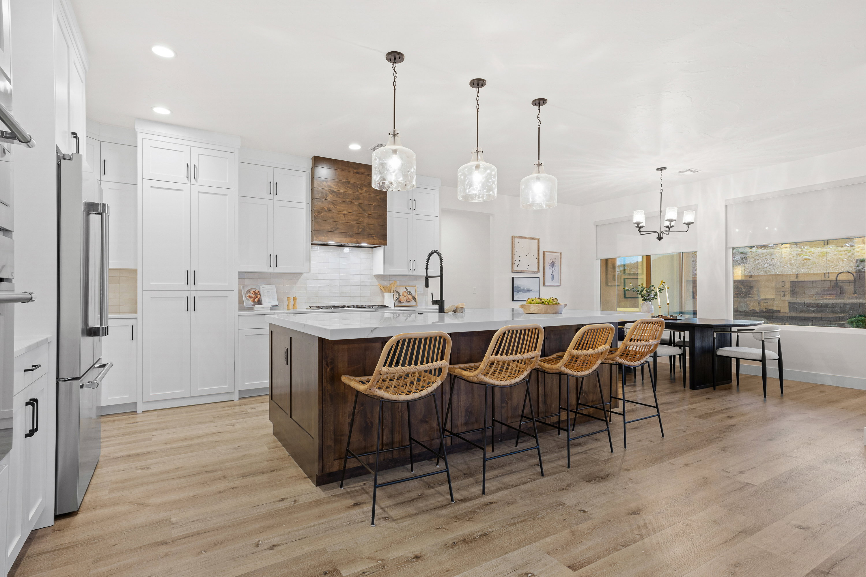 Dual tone kitchen with two tone color scheme, a large island with sink, a kitchen bar, high end fridge, and light wood-style floors