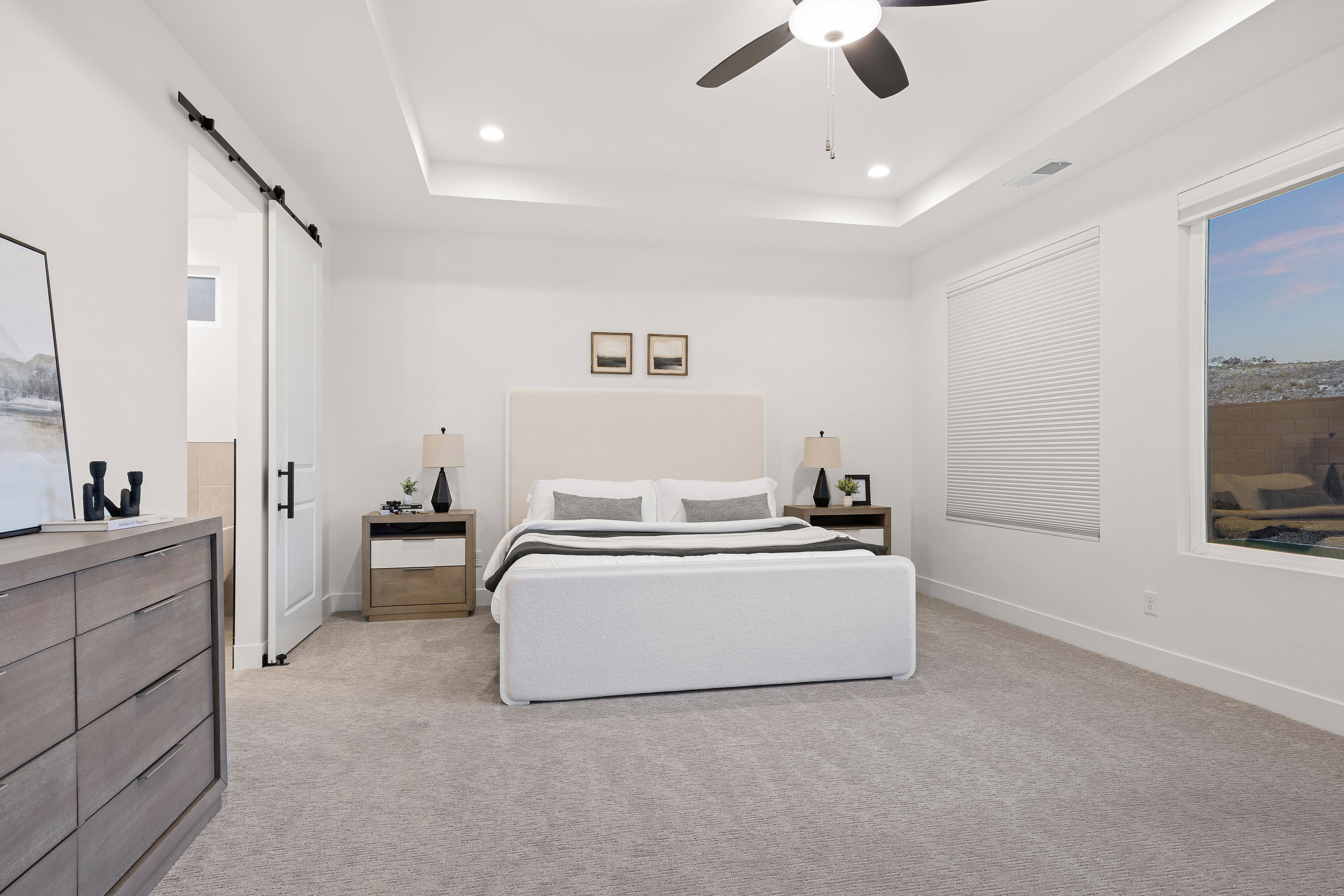 Bedroom featuring a barn door, light colored carpet, ceiling fan, recessed lighting, and a tray ceiling