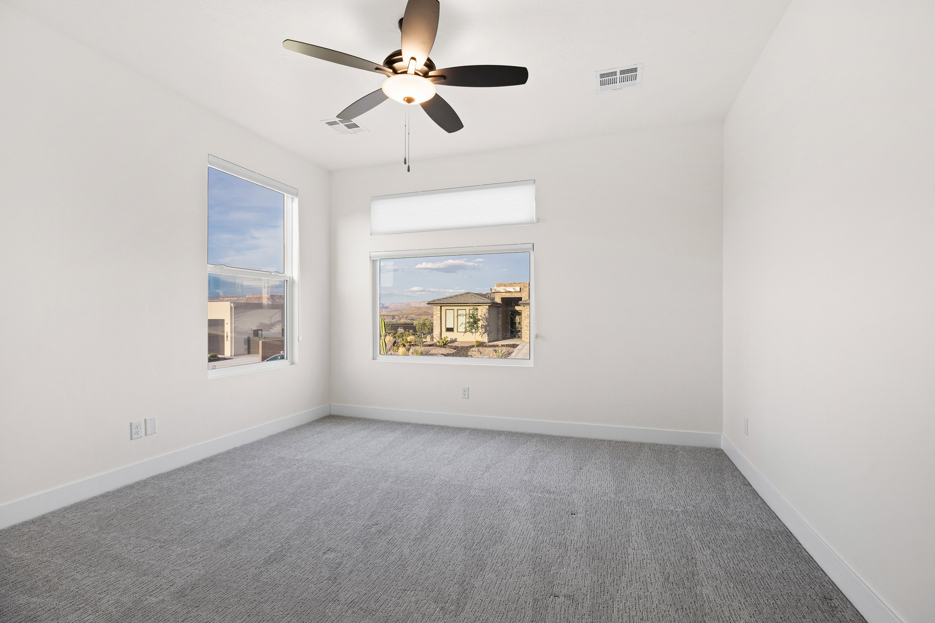 Empty room with a ceiling fan and light colored carpet