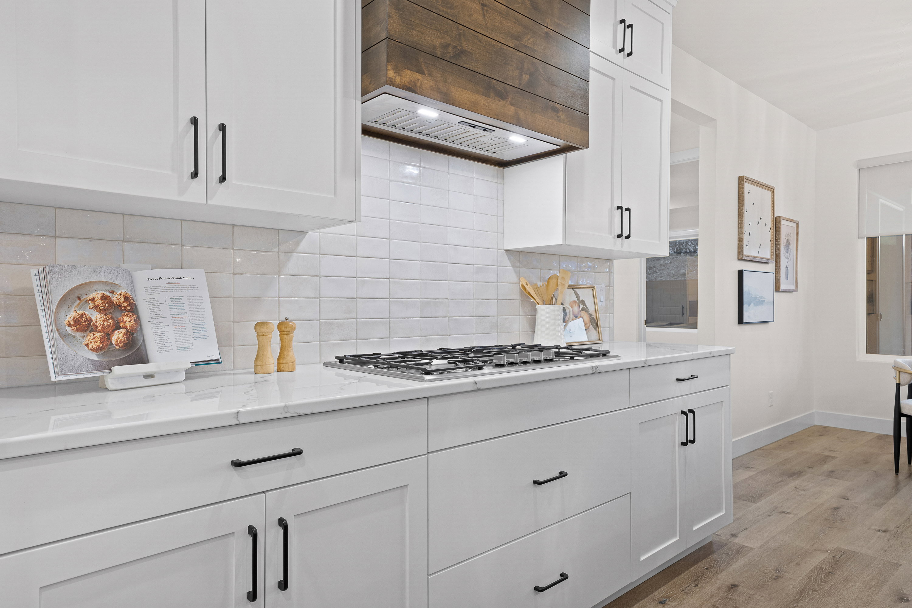 Kitchen featuring white cabinetry, light wood finished floors, backsplash, and light stone countertops