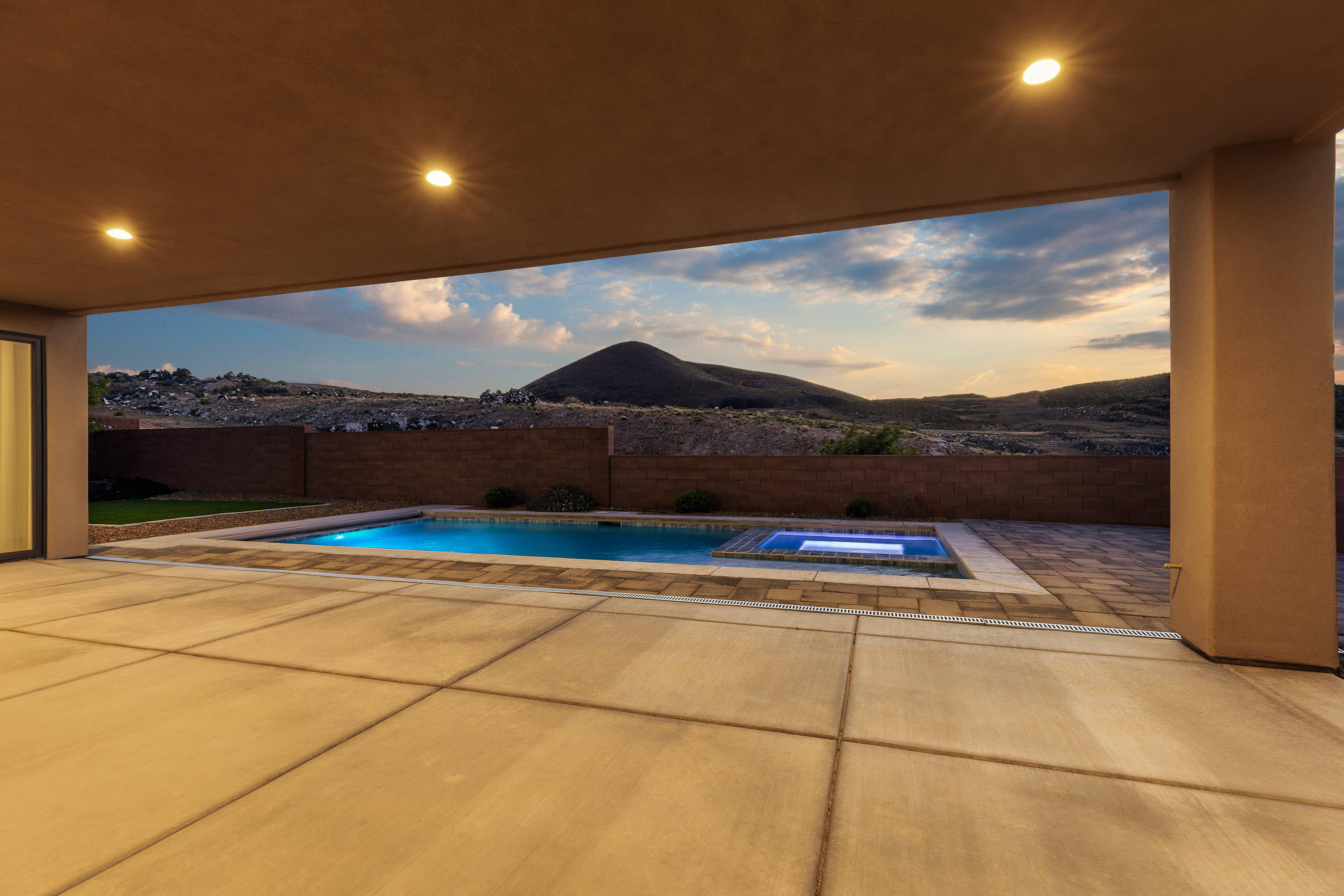 Pool at dusk featuring an in-ground hot tub, a patio area, a mountain view, and a fenced backyard