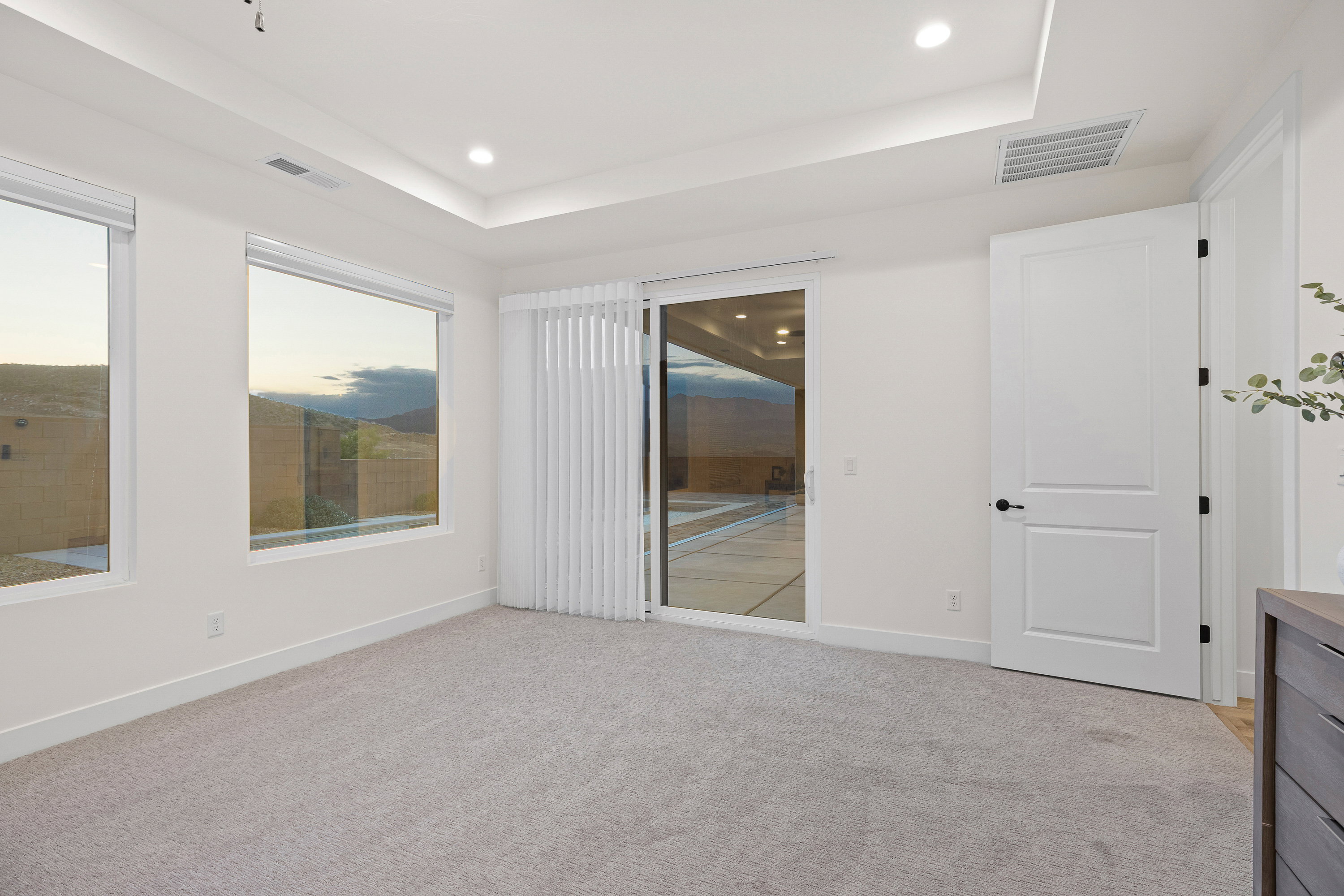 Unfurnished bedroom featuring a raised ceiling, light colored carpet, recessed lighting, and access to outside