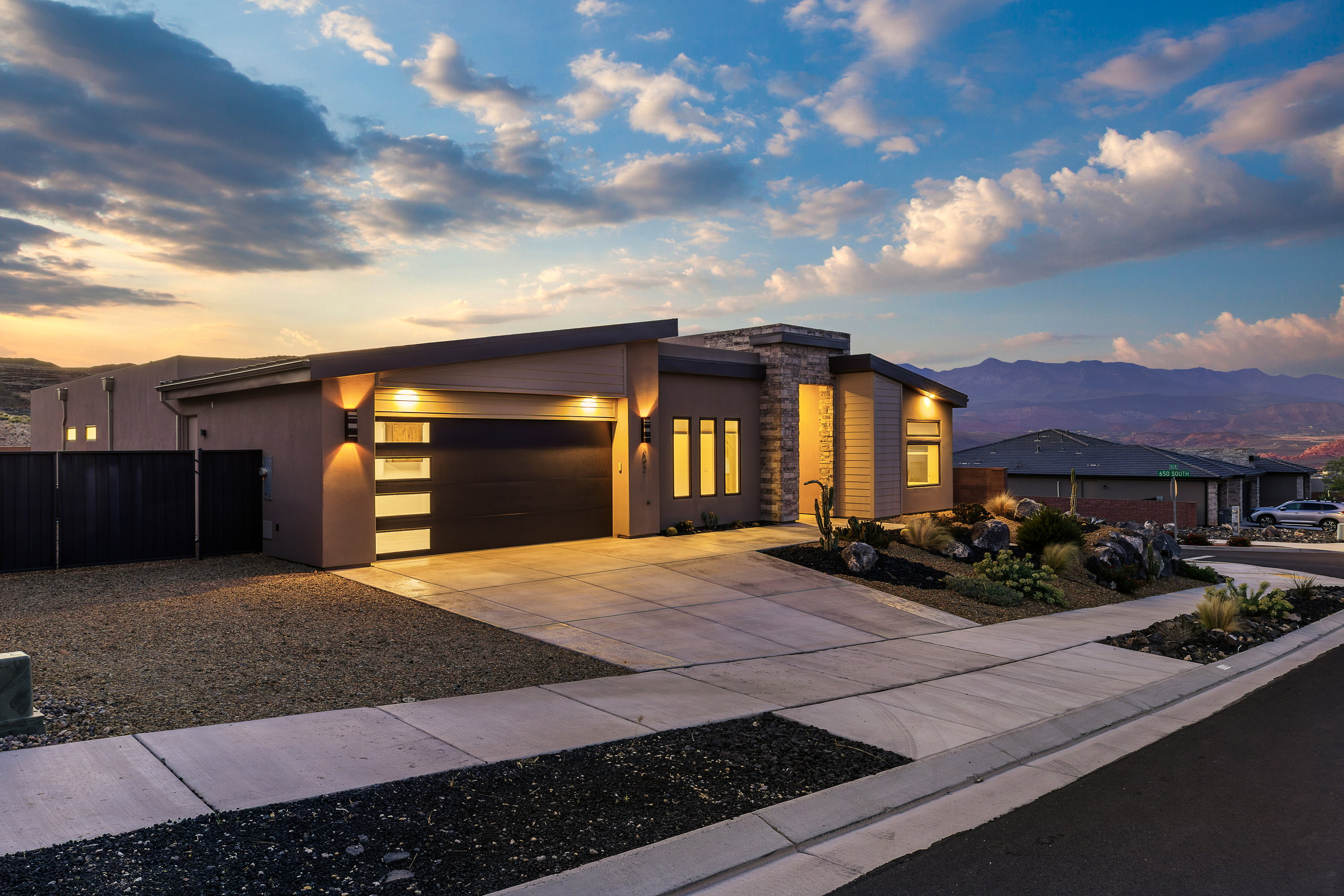 Modern home with stone siding, concrete driveway, a garage, stucco siding, and a mountain view