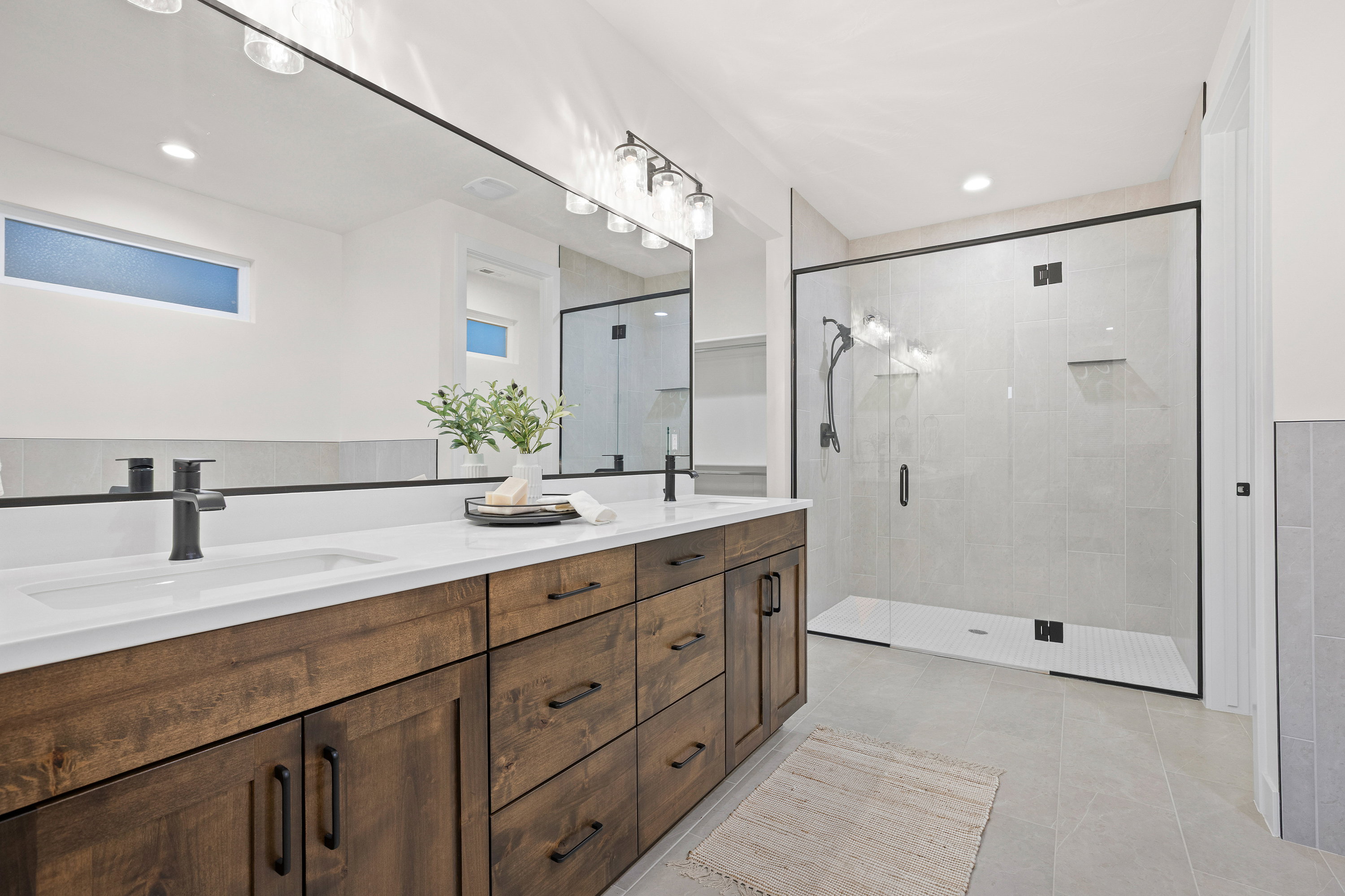 Bathroom featuring double vanity, a stall shower, light tile patterned flooring, and recessed lighting