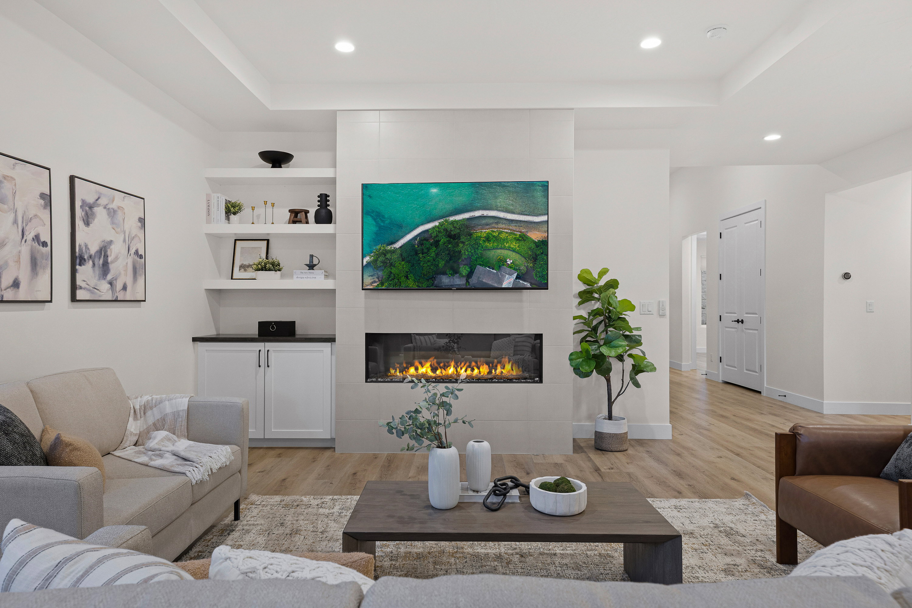 Living area with light wood-style floors, a fireplace, recessed lighting, and a tray ceiling
