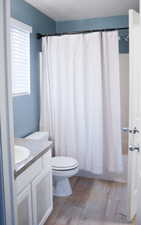 Full bathroom with vanity, light wood-style flooring, and shower / bath combination with curtain