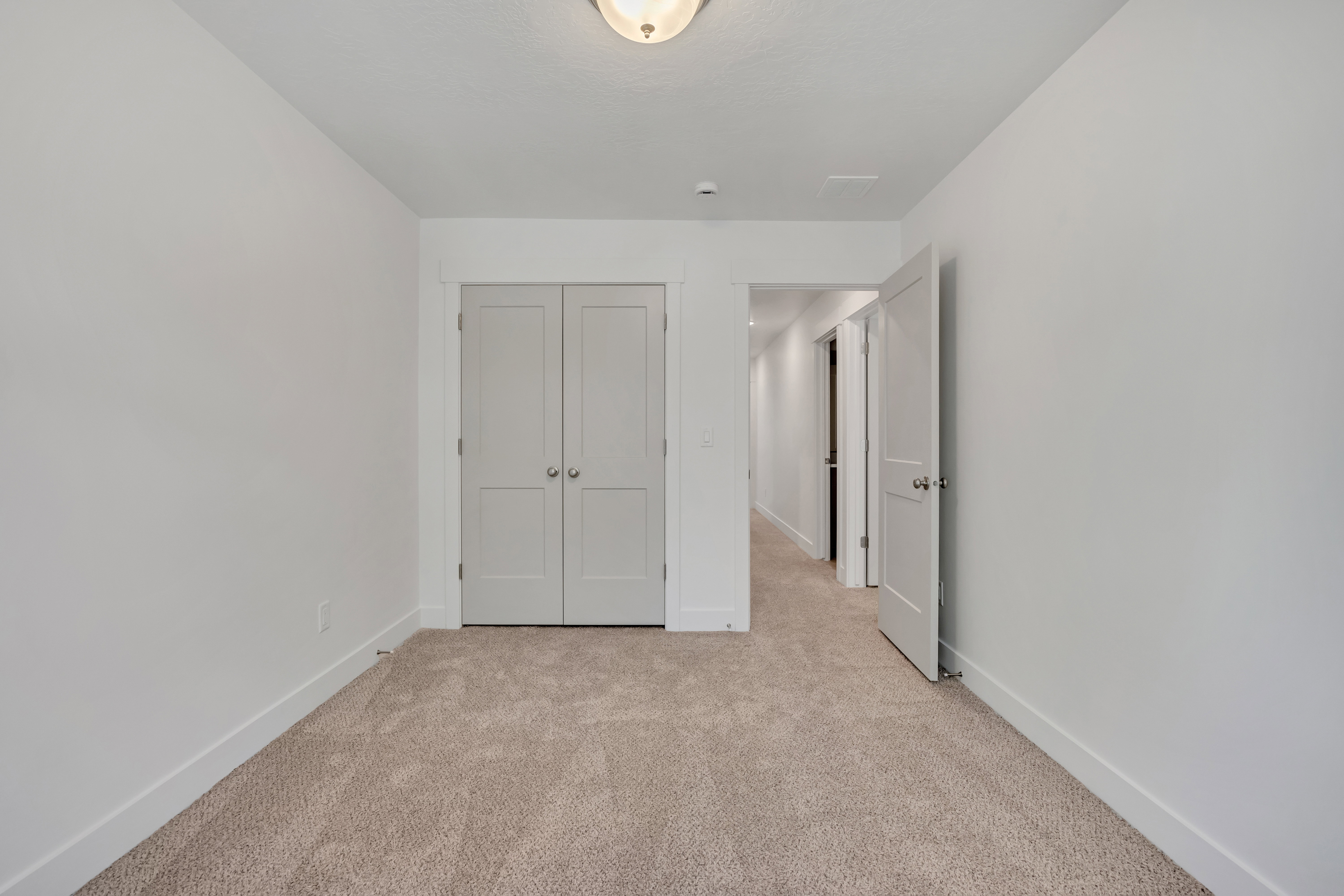 Neutral tone carpet flooring with white baseboards and walls