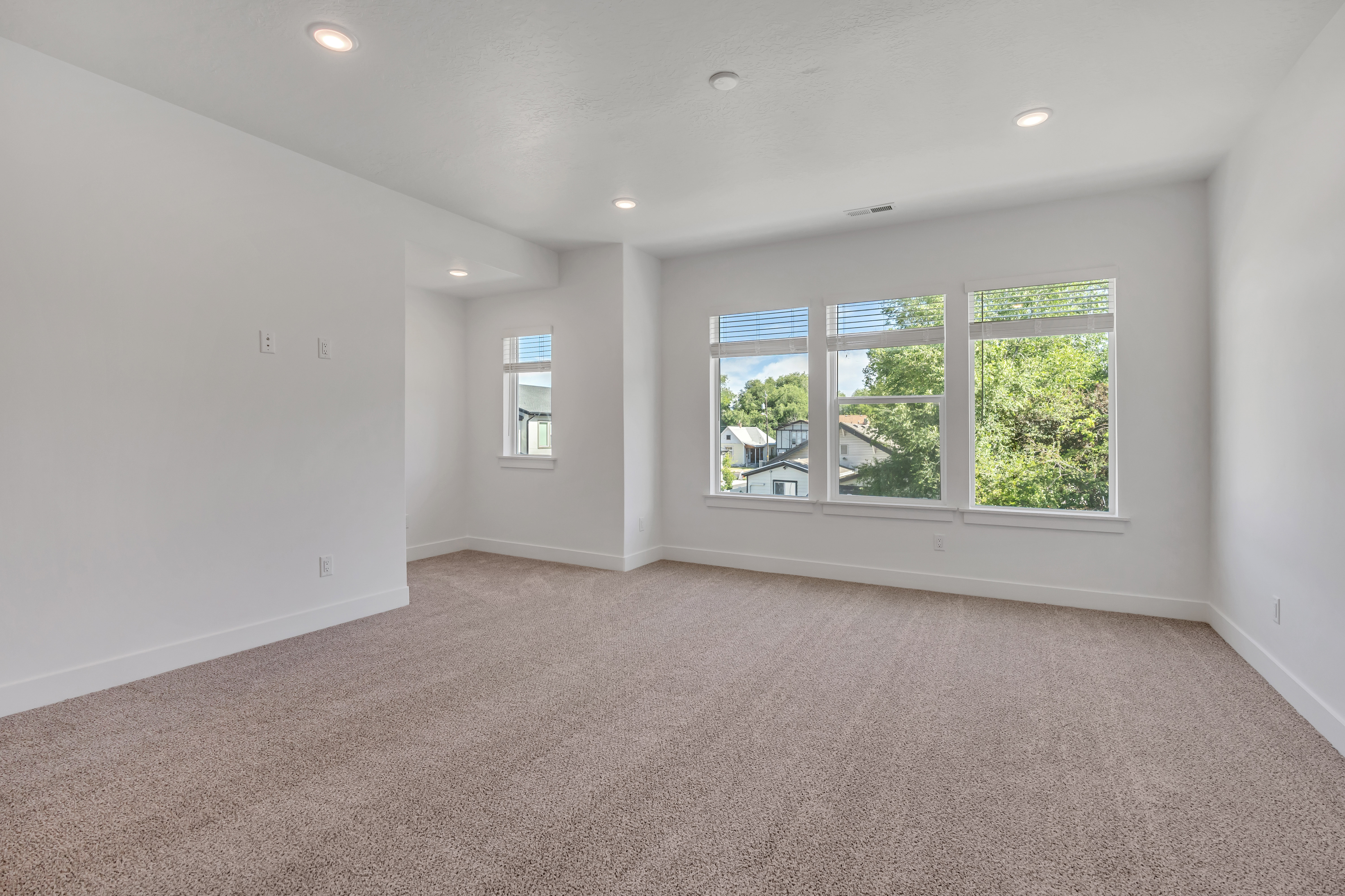 Spacious room with plush carpeting, recessed lighting, and multiple windows