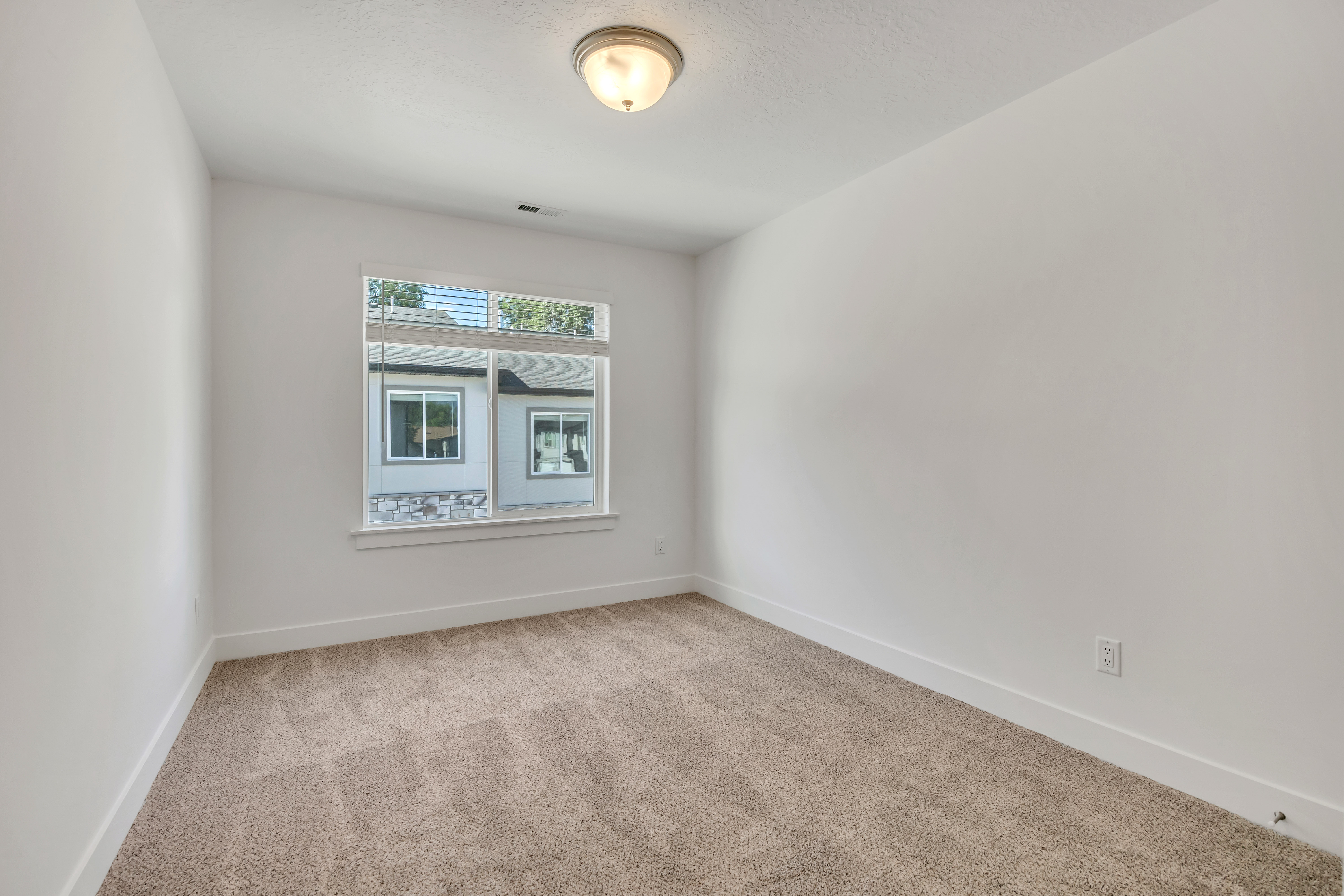 Carpeted room with a ceiling-mounted light fixture and a single window