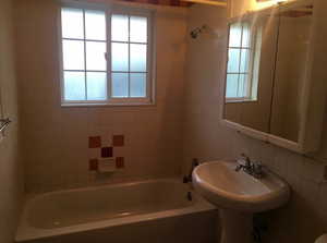 Bathroom with shower / tub combination, tile walls, and tasteful backsplash