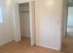 Unfurnished bedroom featuring light wood-type flooring and a closet